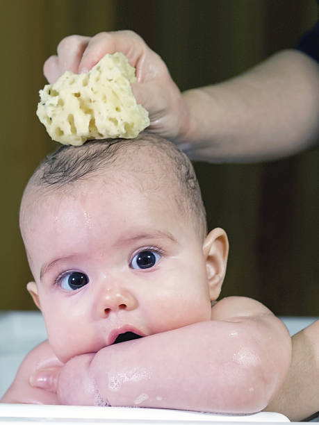 istock baby girl smiles during bathing supported by mom 477614851