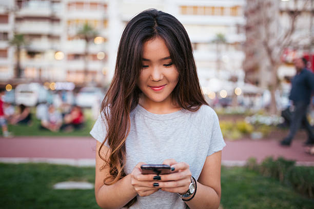 азиатская молодая женщина, с помощью телефона - alohalypse стоковые фото и изображения