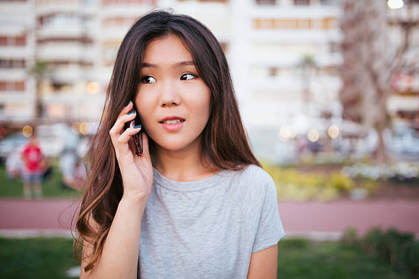 азиатская молодая женщина, с помощью телефона - alohalypse стоковые фото и изображения