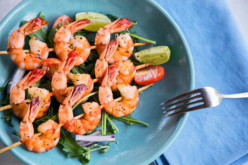 Grilled shrimps on skews with salad and lime slices