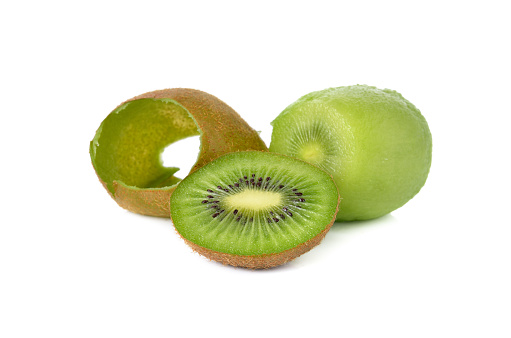 Fresh whole and sliced kiwi fruit in a metal bowl on a black and gray background