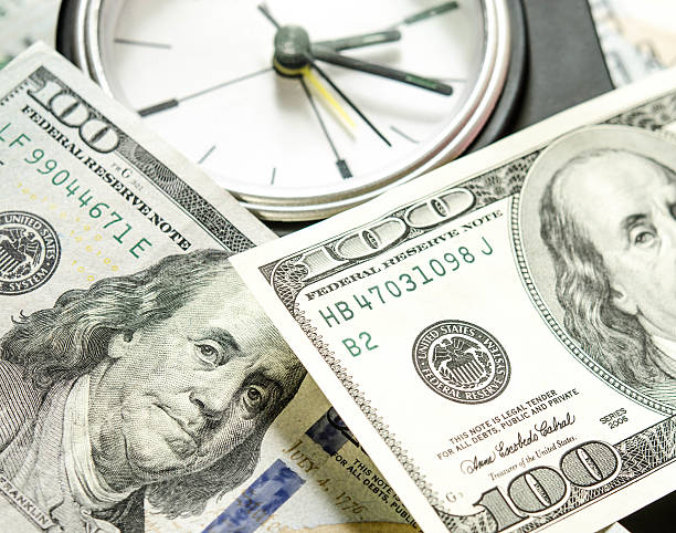 Stack of one hundred dollar bills with clock. Dof view stock photo