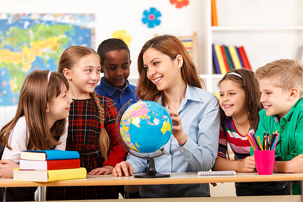 istock Teacher and children looking at globe 477633505