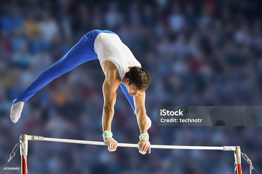Male gymnast performing routine on horizontal bar Side view of young man performing short routine on horizontal bar, artistic gymnastics Gymnastics Stock Photo