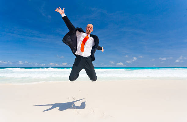 istock overjoyed jumping business man on the beach 477639859