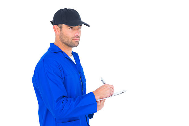 istock Mechanic in blue overalls writing on clipboard 477640446