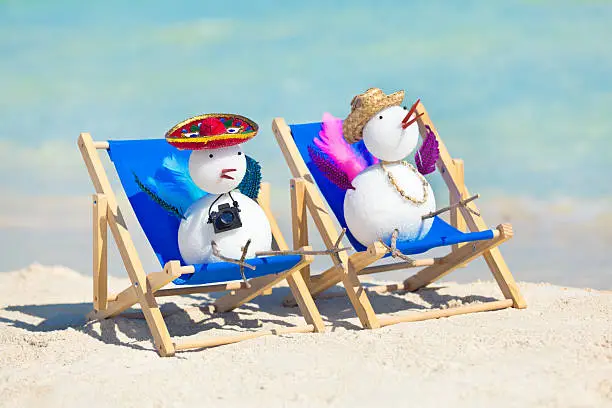 A snowbird couple Christmas winter holiday vacationing on a tropical beach of Mexico. Snowbird, a common word for Northern cold climate travelers and vacationers moving south to tropical warm weather during winter season to escape the cold weather. Photographed on location in Caribbean Mexico in horizontal format.