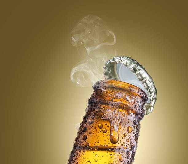 close-up of beer bottleneck with droplets, ice, smoke, and cap stock photo
