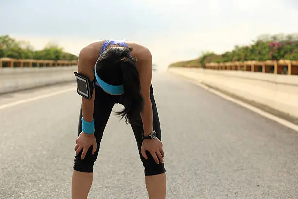 Photo of tired woman runner taking a rest after running hard