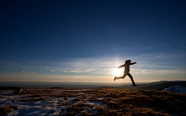 silhouette of man running in sunset sky stock photo