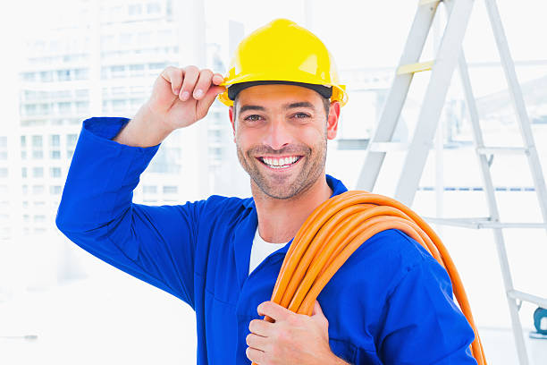 istock Confident repairman wearing hard hat while holding wire roll 477644472