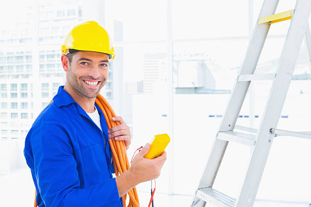 Smiling male electrician holding multimeter in office Portrait of smiling male electrician holding multimeter in bright office electrician smiling stock pictures, royalty-free photos & images