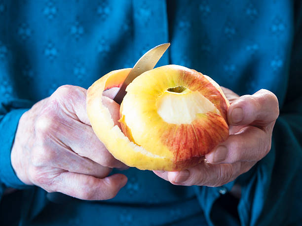 Elderly hands peeling an apple stock photo