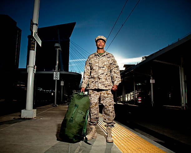 US Marine Soldier Coming Home US Marine soldier with a duffle bag at the train station. The model is wearing an official US Marine corps Marpat BDU uniform. military deployment photos stock pictures, royalty-free photos & images