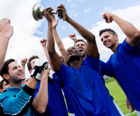 Happy soccer team celebrating a victory and lifting a trophy