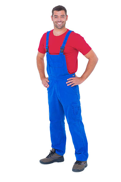 istock Happy handyman in overalls with hands on hip 477659208