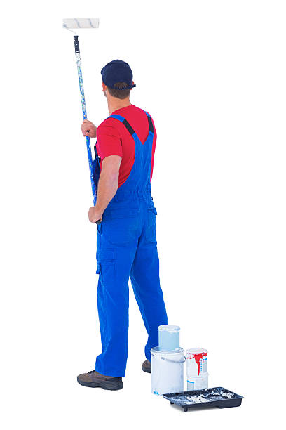 istock Rear view of handyman painting with roller on white background 477659802