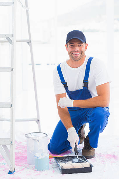 istock Portrait of smiling handyman using paint roller in tray 477660474