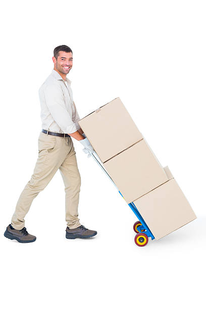 istock Happy delivery man pushing trolley of boxes 477663066