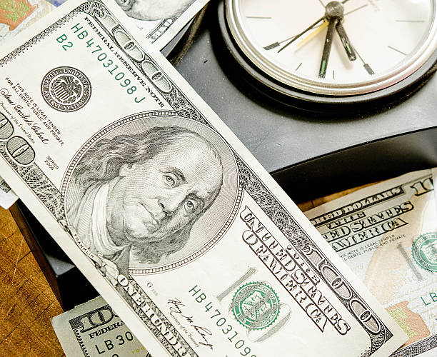 Stack of one hundred dollar bills with clock. Dof view stock photo