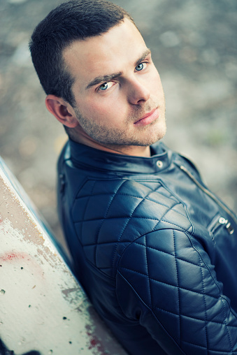 Outdoor Portrait of Handsome Stylish Young Man. With blue eyes and brown hair, wearing leather jacket.