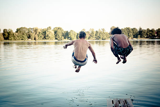 istock carefree summer day: teenagers jumping into a lake 477670457