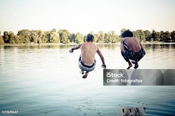 Carefree Summer Day Teenagers Jumping Into A Lake Stock Photo - Download Image Now - Adolescence, Carefree, Cheerful