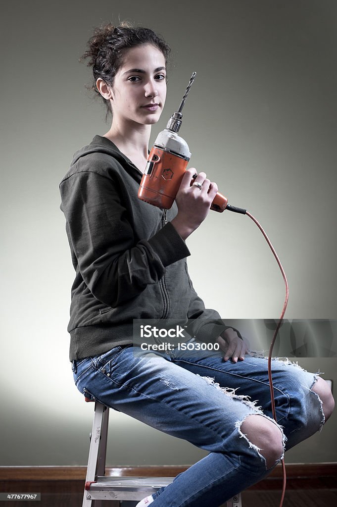 Young female holding a drill Young female holding a drill while sitting on ladder Adult Stock Photo