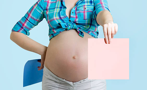 istock Pregnant beautiful young woman with blank post-it note. 477682774