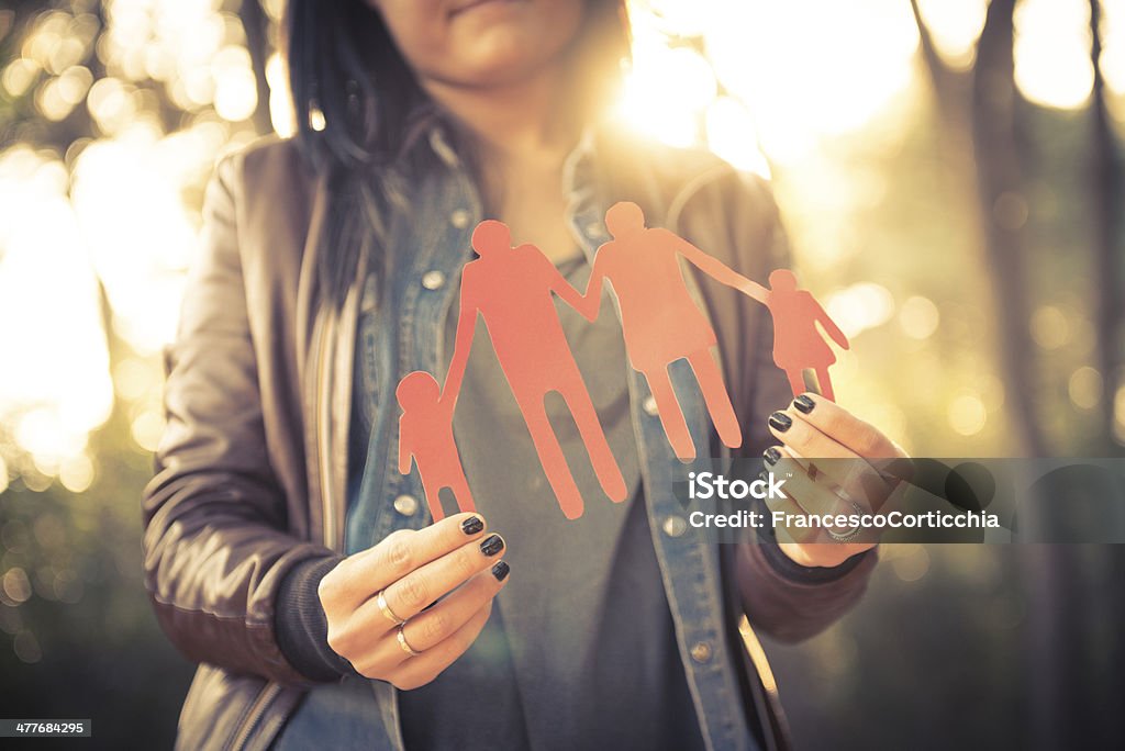 Family paper dools Young caucasian woman holding an entire family of paper dolls in her hand. Adult Stock Photo