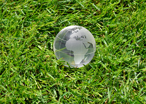 Close up of a mass produced glass globe focusing on Europe and Africa on a grass background.  