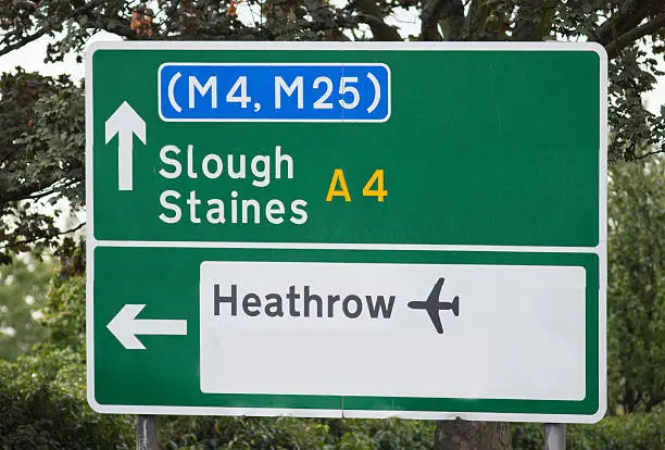 Green British road sign showing direction to Heathrow Airport, Slough and Staines.