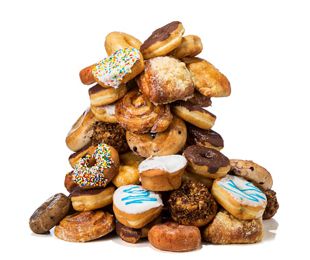 A large assortment of donuts, bagels, muffins and pastries in a large heap on a white background.  Please see my portfolio for other food related images. 