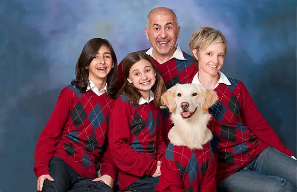 Humorous family portrait with golden retriever dog all in cardigans.