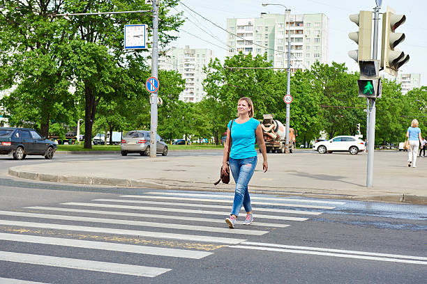 istock Young woman crossing road at green light 477689002