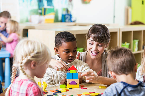 istock Kindergarten teacher with group of children in classroom 477689190