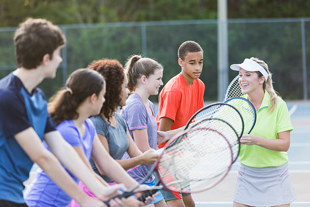 Teenagers at tennis clinic Multi-ethnic group of teenagers (14 to 17 years) at tennis clinic with instructor (30s).  Main focus on boy in red shirt (14 years, mixed race African American / Caucasian). tennis coach stock pictures, royalty-free photos & images