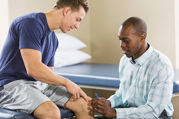 Physical therapist examining patient Physical therapist examining patient, testing reflexes with reflex hammer. orthopedist stock pictures, royalty-free photos & images