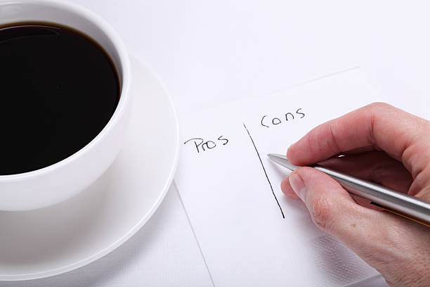 Pros and Cons on a Napkin Pros and Cons on a Napkin. (Focus on fingers) pros and cons stock pictures, royalty-free photos & images