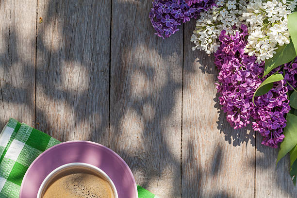 istock Coffee cup and colorful lilac flowers on garden table 477693364
