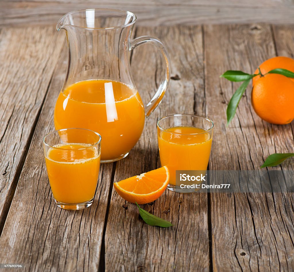 Fruits and orange juice Glassfuls and pitcher of orange juice on a old wooden table 2015 Stock Photo