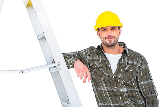 istock Smiling handyman in overalls leaning on ladder 477693752