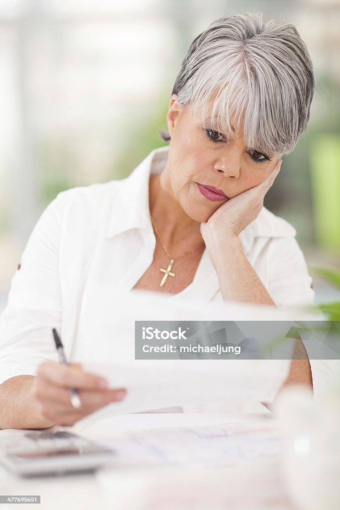 stressed senior woman paying her bills stressed senior woman paying her bills at home Adult Stock Photo