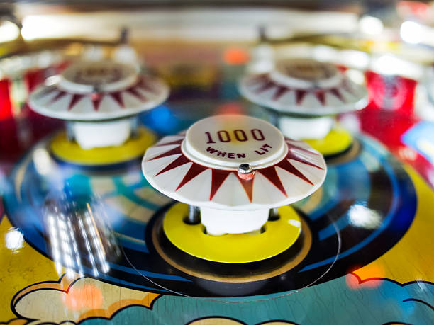 Antique Pinball Machine with Ball in motion The bumpers from an antique pinball machine from the 1960s, the ball in motion moving toward the bumper on the left in the background. pinball machine stock pictures, royalty-free photos & images