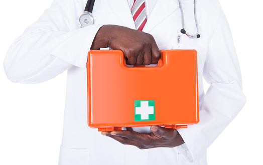 Young Male African Doctor Holding First Aid Box Over White Background