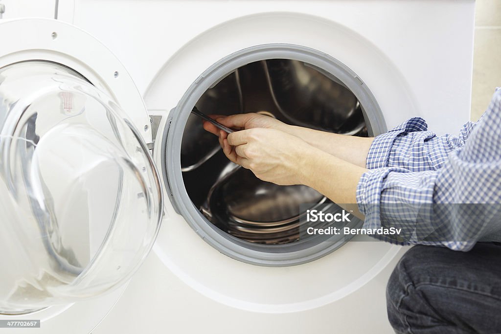 handyman repairing a washing machine Repairing Stock Photo
