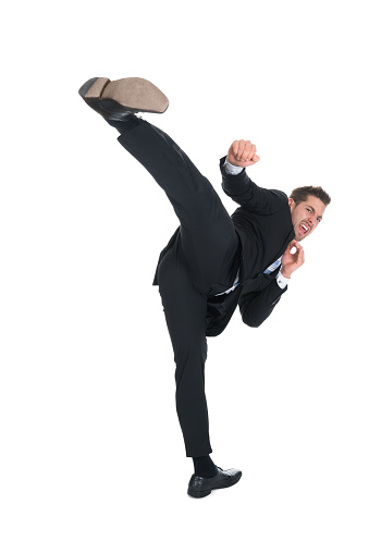 Full length of young businessman kicking over white background