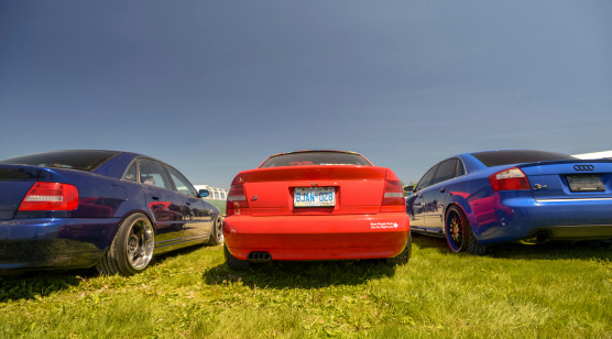 Toronto, Ontario, Canada- May 25, 2013. Fitted: Alternative Car scene  Outdoor custom car show in Toronto, Ontario. Three Audi sports sedan cars parked on the grass. Focus on the rear end. All cars lowered to the ground. Large wheels with low profile tires.