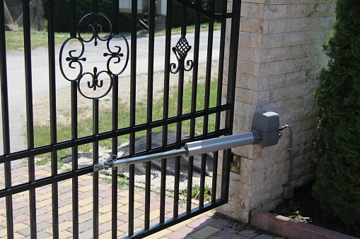 Closed electric iron gate with brick fence.