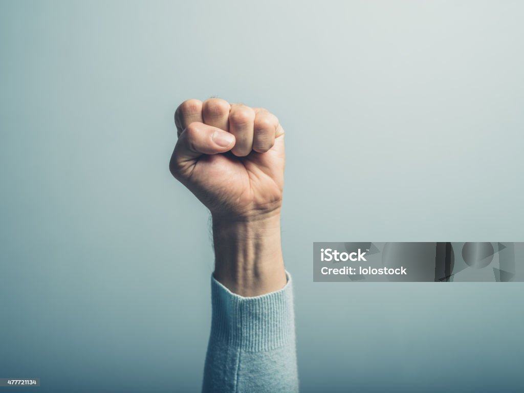 Fist in the air A clenched male fist is up in the air Courage Stock Photo